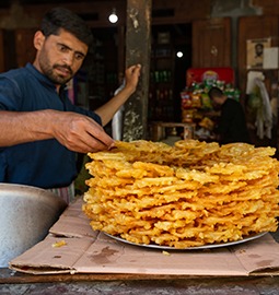 HUNZA, PAKISTAN - September 2021: Pakistani man selling jalebi sweets on the market in Hunza Valley, Pakistan